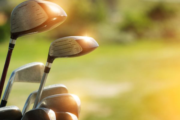 Golf clubs drivers over green field background