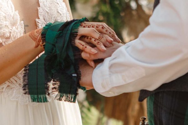 A man and woman in Scottish dress with handfasting ceremony.