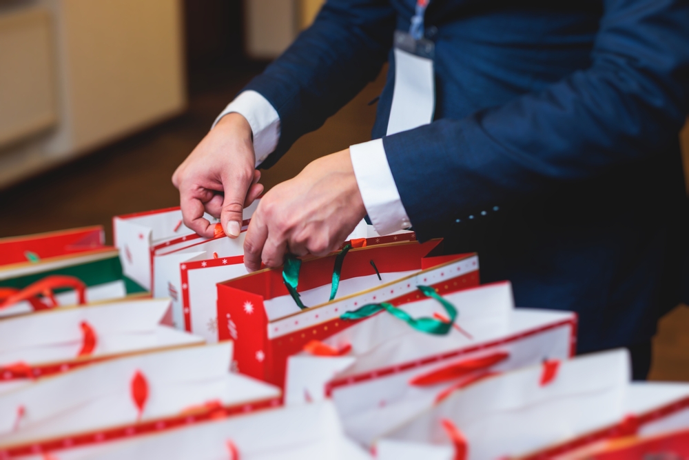 Christmas party surprise gift bag, gift giving at office work, red green and white paper bags, presents exchange with colleagues at work.