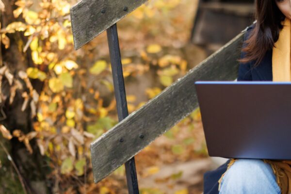 woman sitting on a step working on her laptop in autumn.